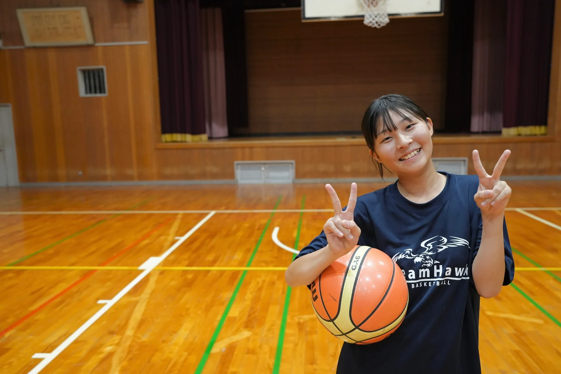 バスケットボールを抱えて笑顔でピースするDreamHawksの選手